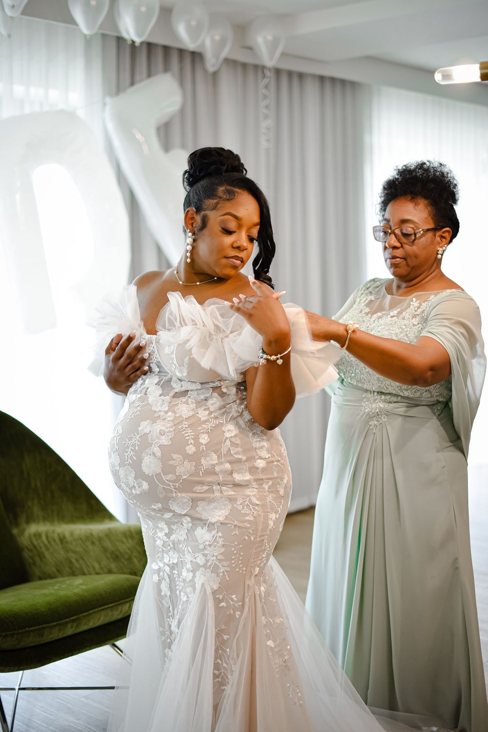 Beautiful wedding dress fitting session with intricate lace details and sage green accents.