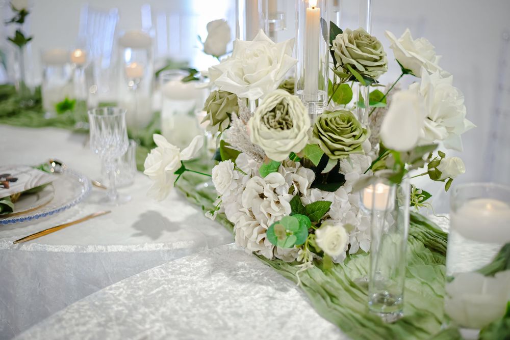 Elegant white floral table centerpiece with crystal glassware for a wedding reception.