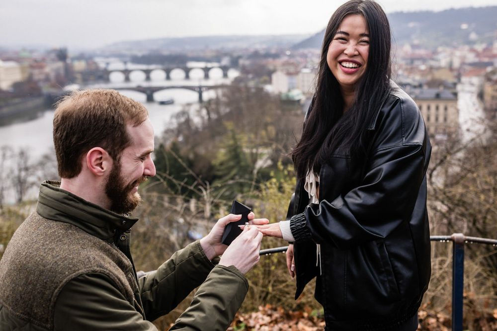A couple shares joyful moments together while exploring a scenic overlook with city views in the background.
