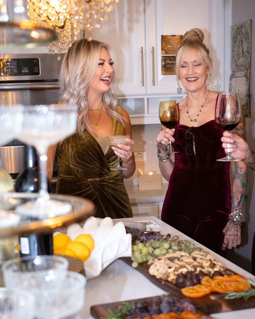 Two people enjoying wine and conversation in an elegant kitchen setting with warm lighting and holiday decorations.
