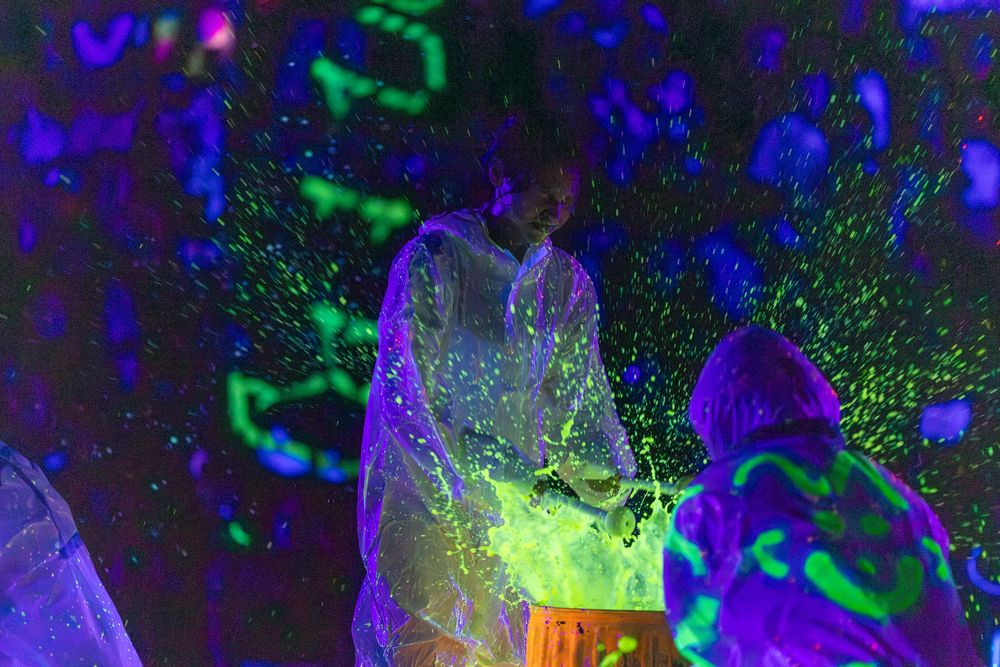 Abstract digital artwork with swirling neon blue and green lights against a dark background creates a cosmic effect.