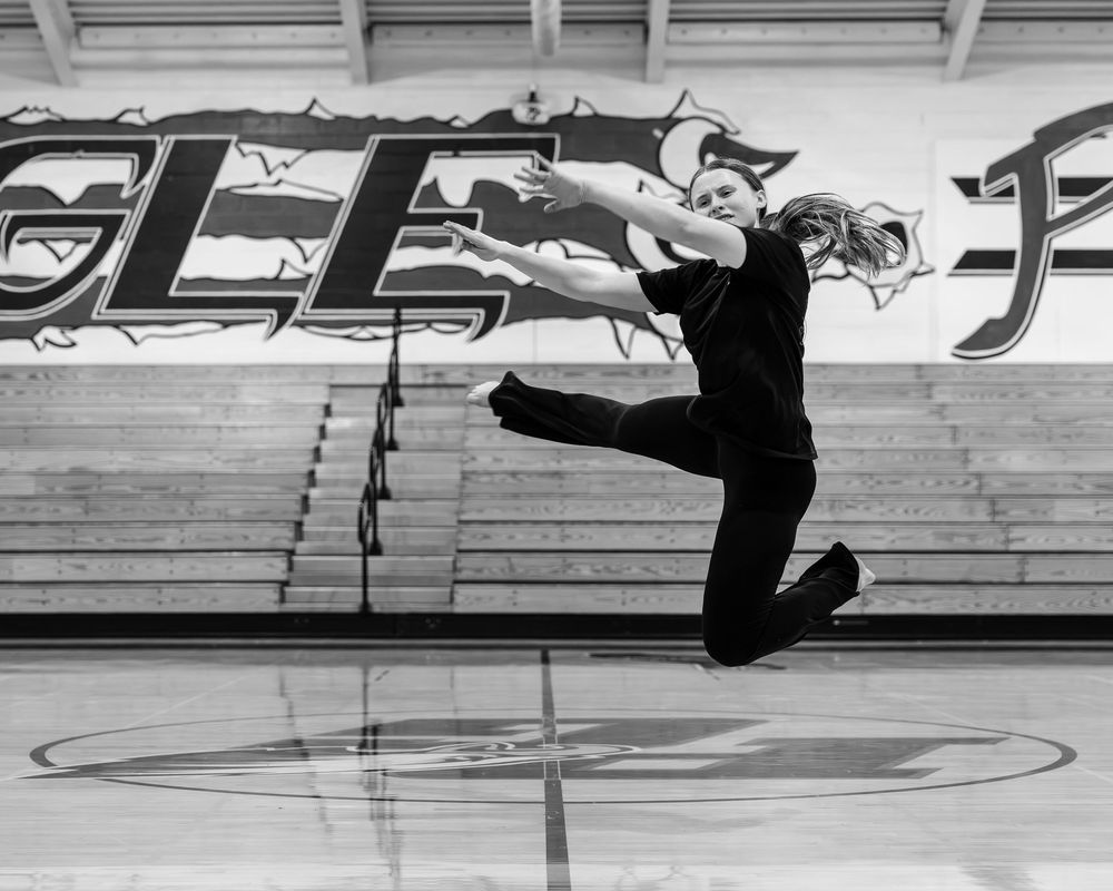 A sequence of black and white photos showing a figure performing a breakdancing windmill move on a wooden floor.