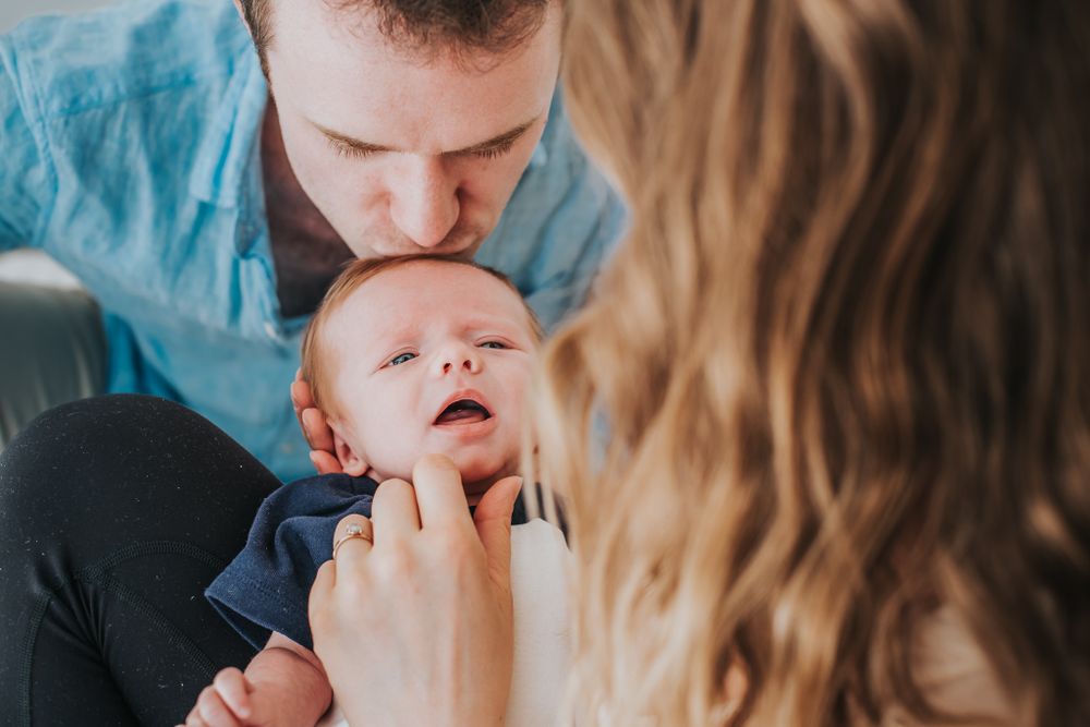 A caucasian mother and father hold and look at their newborn baby.
