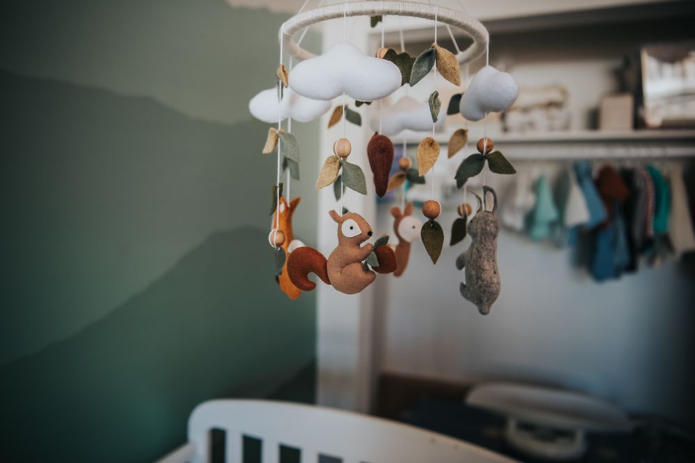 Felt woodland creature mobile hanging in a baby nursery.