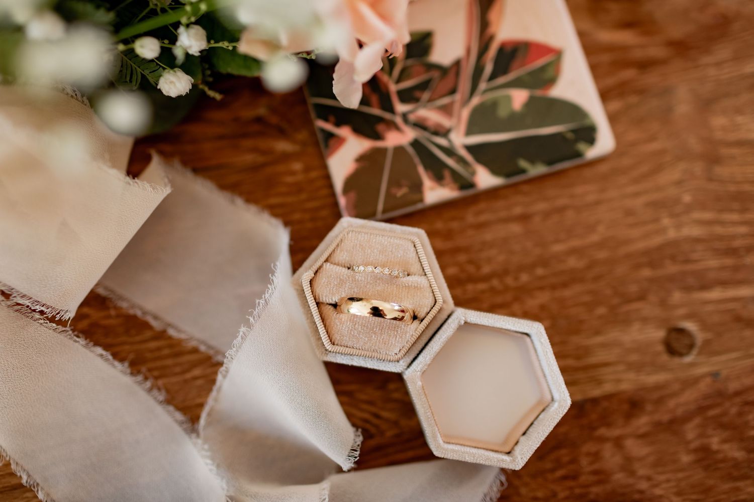 Hexagonal wedding ring boxes with silk ribbon on rustic wooden surface.
