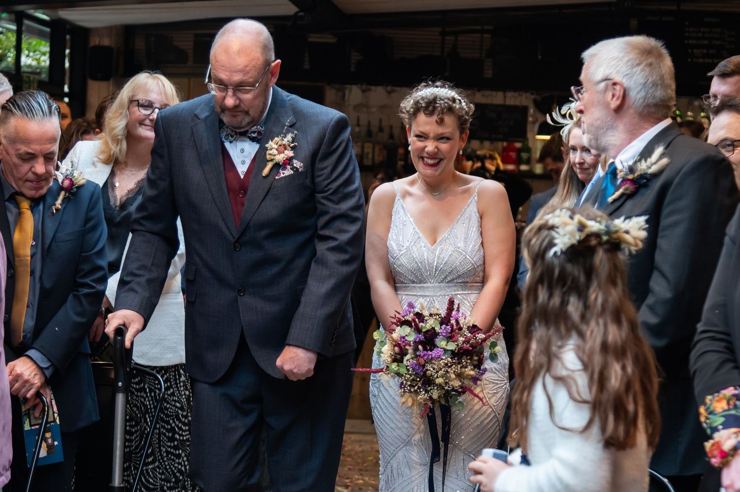 Wedding guests laugh and smile during a joyful celebration at a rustic venue.