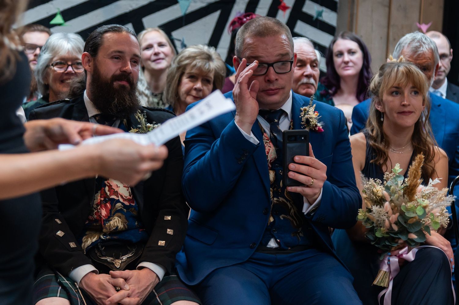 People gathered in formal attire share emotional moments at a wedding celebration.