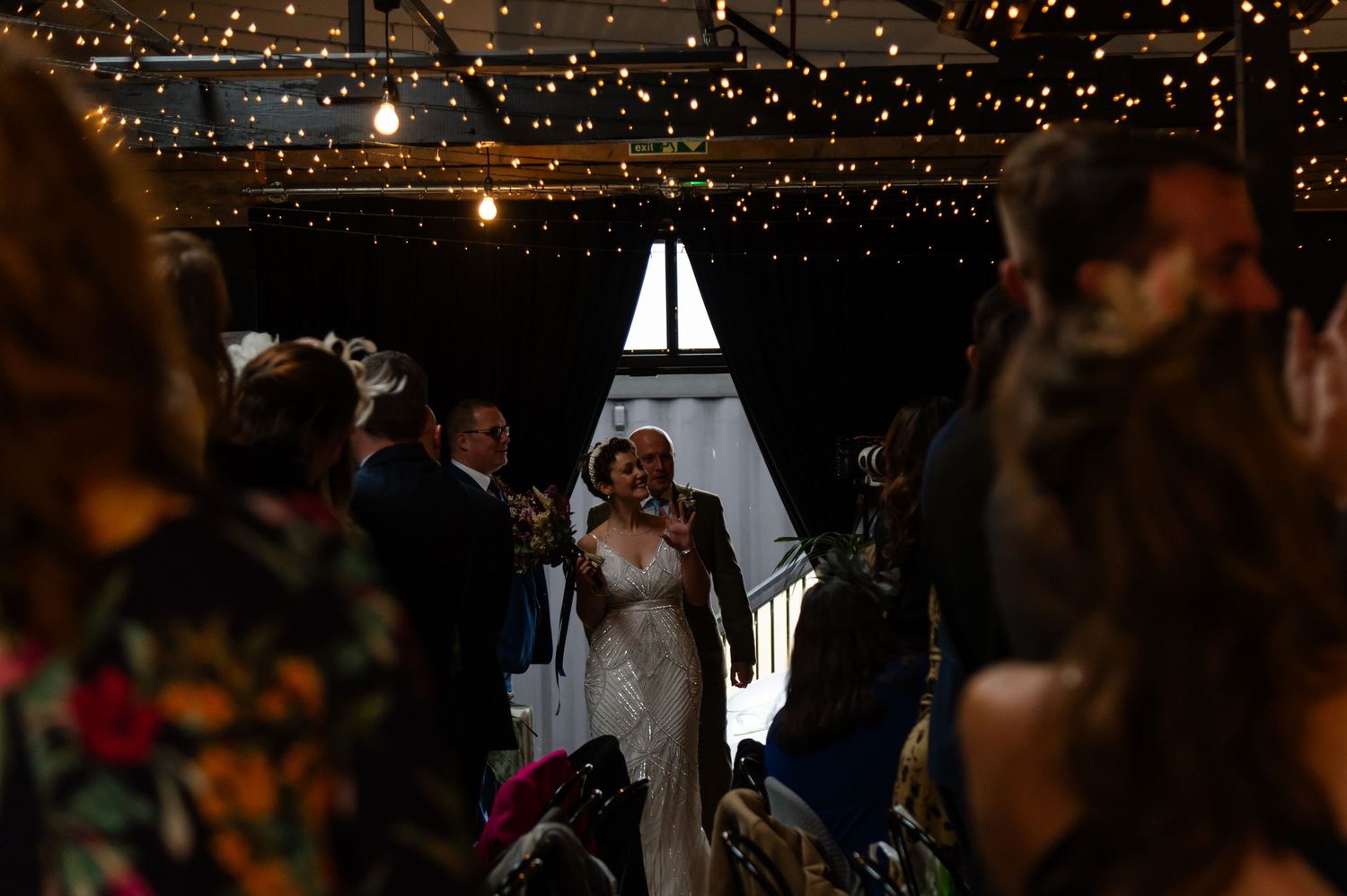 Warm glowing string lights create romantic ambiance at indoor wedding venue.