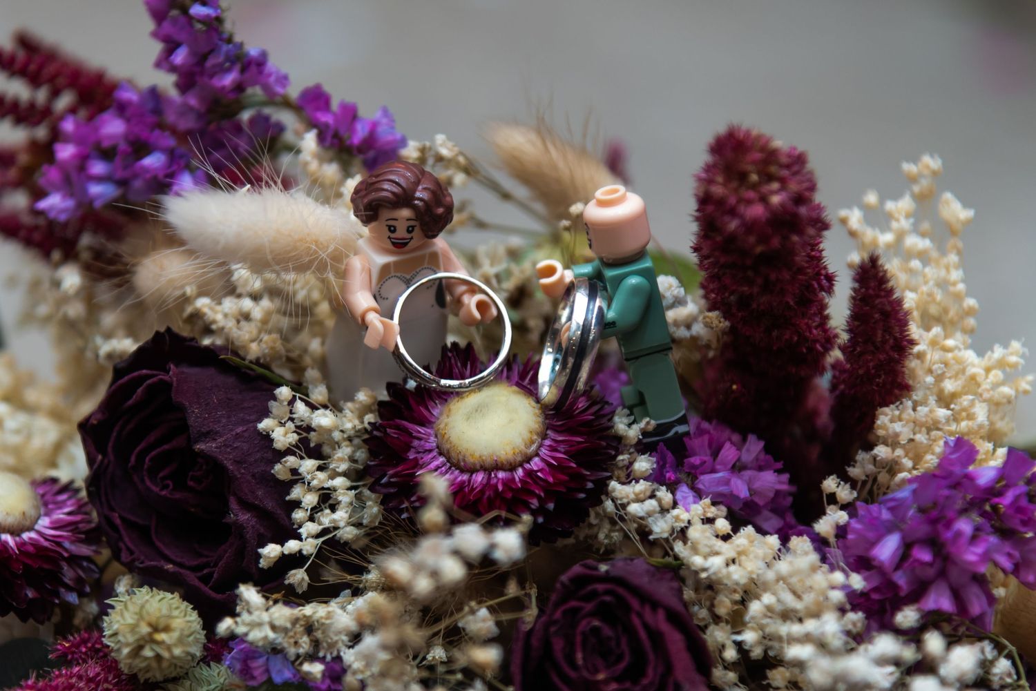 Wedding bouquet featuring deep purple and burgundy flowers with dried elements.