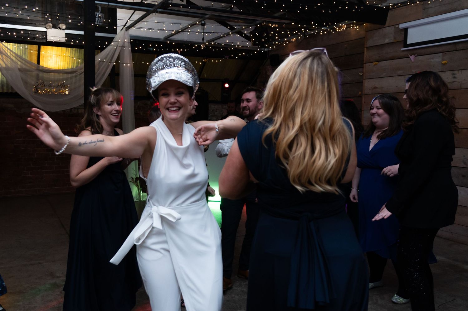 A celebratory dance moment captured at a wedding reception with string lights overhead.