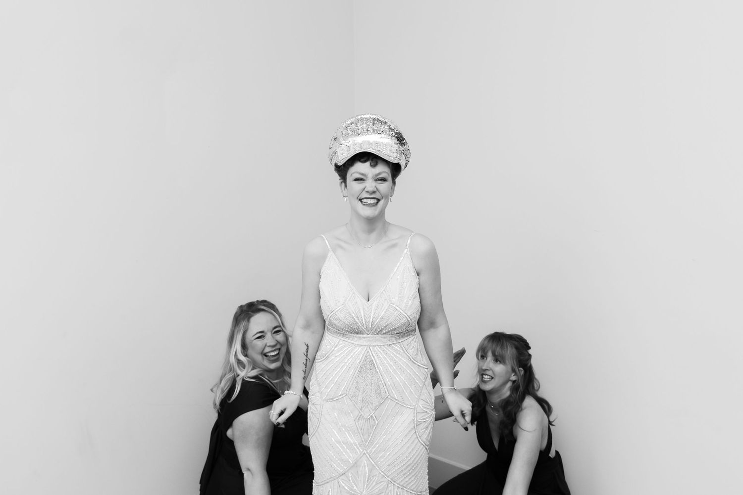 Wedding party group photo against white backdrop in formal attire.