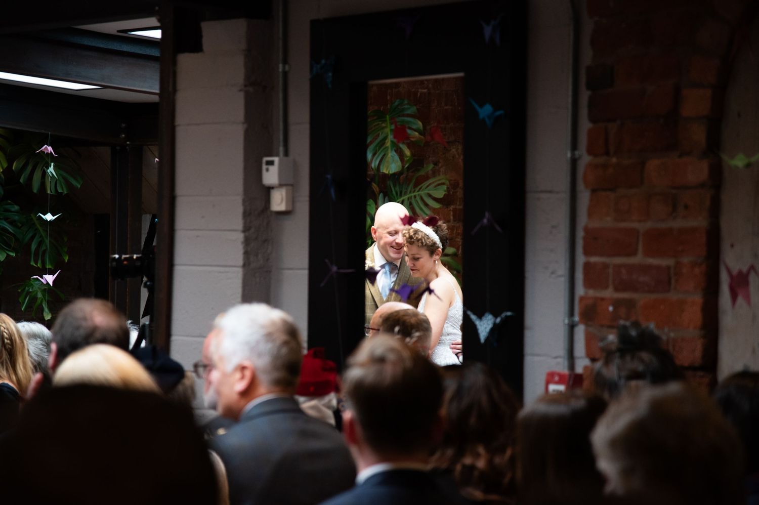 Interior of rustic brick wedding venue with guests in attendance.