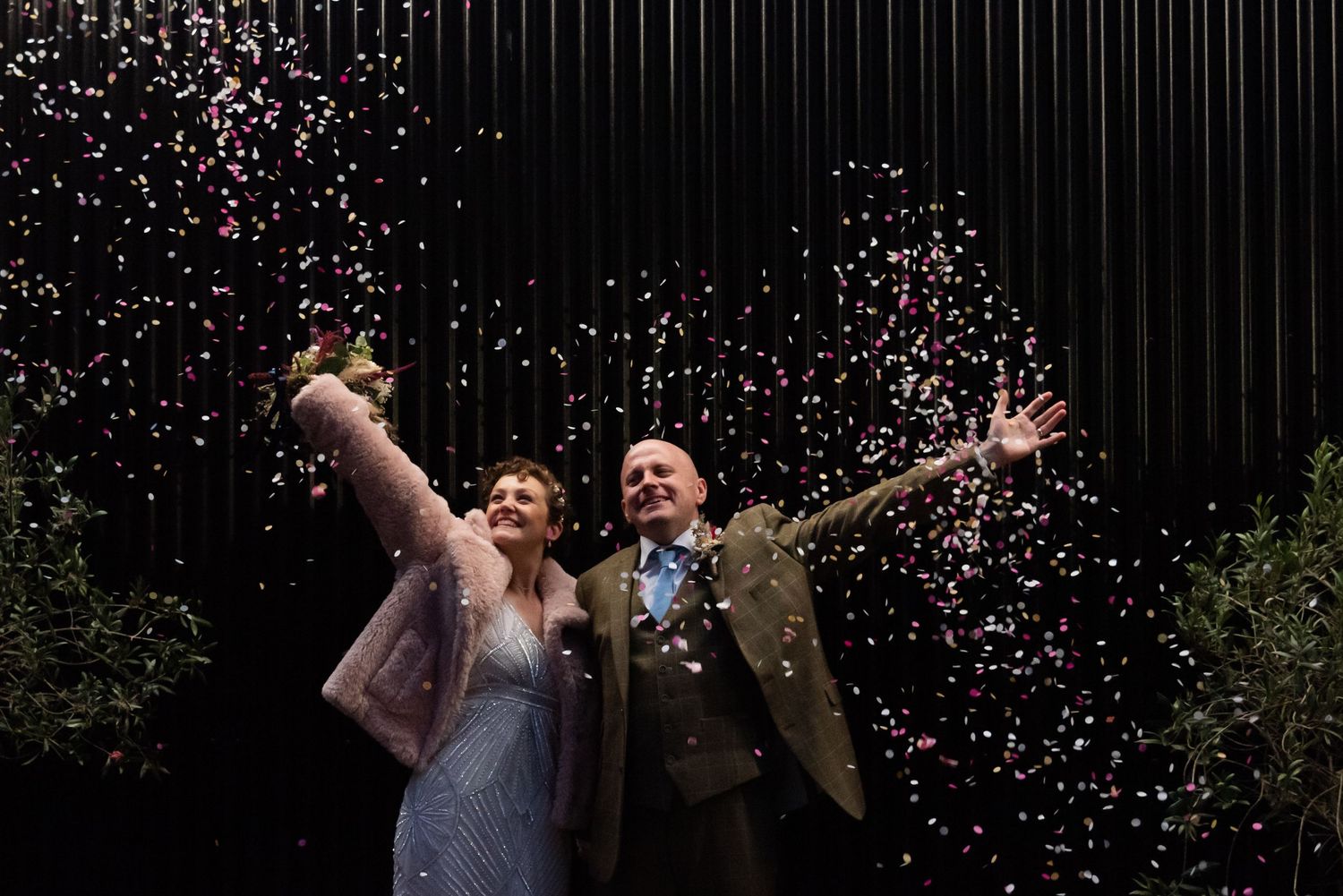 Confetti falling over celebrating guests at a nighttime party.