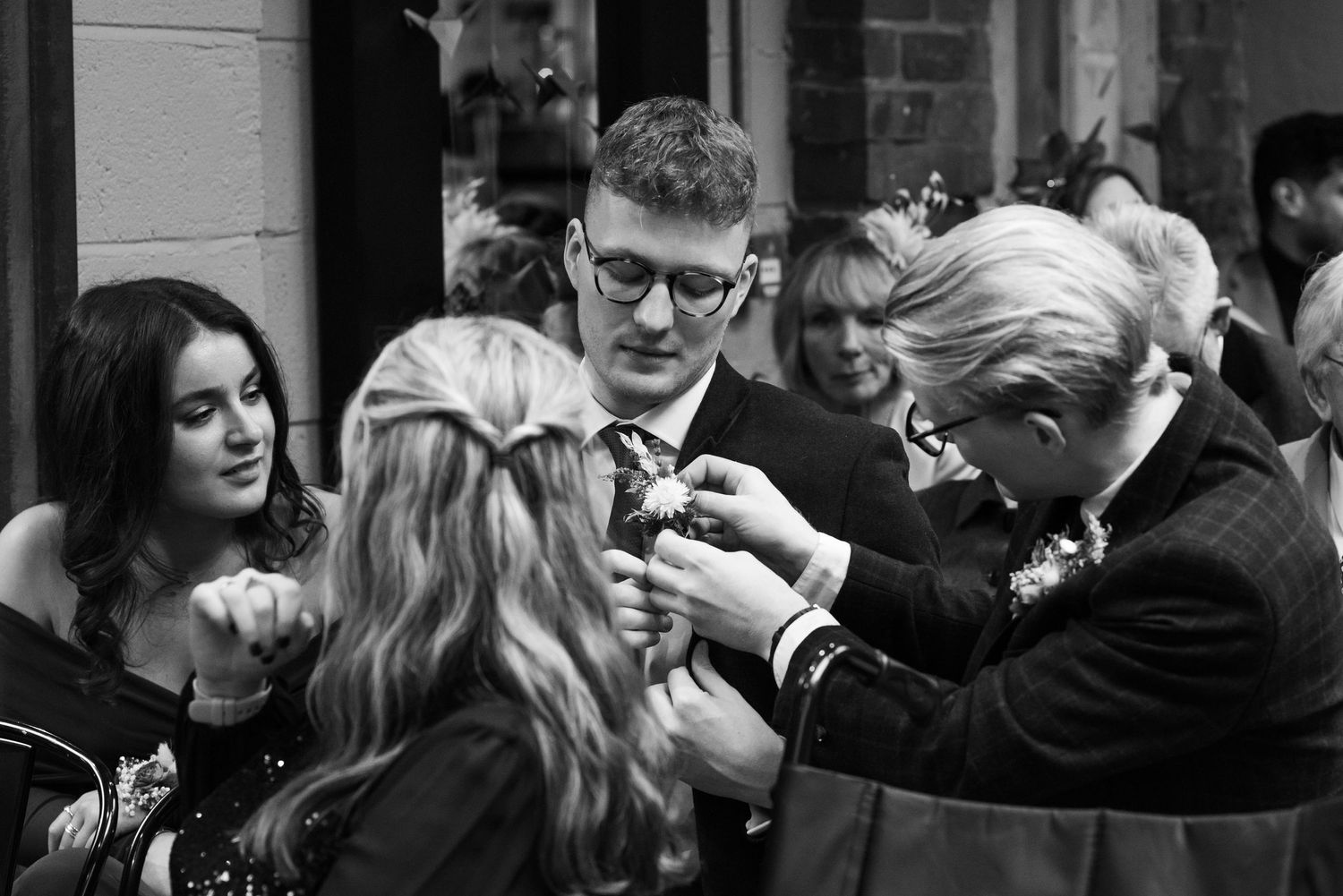 Wedding guests mingling in dimly lit venue with brick walls.