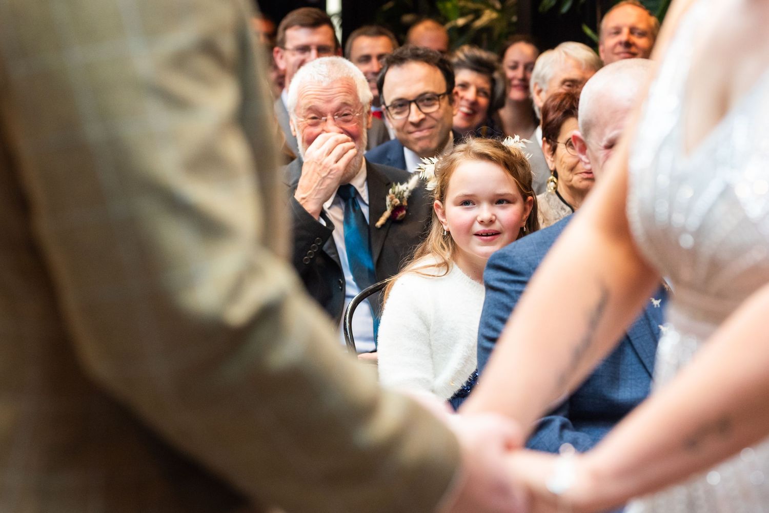 Wedding attendees react emotionally during ceremony in front of exposed brick wall.