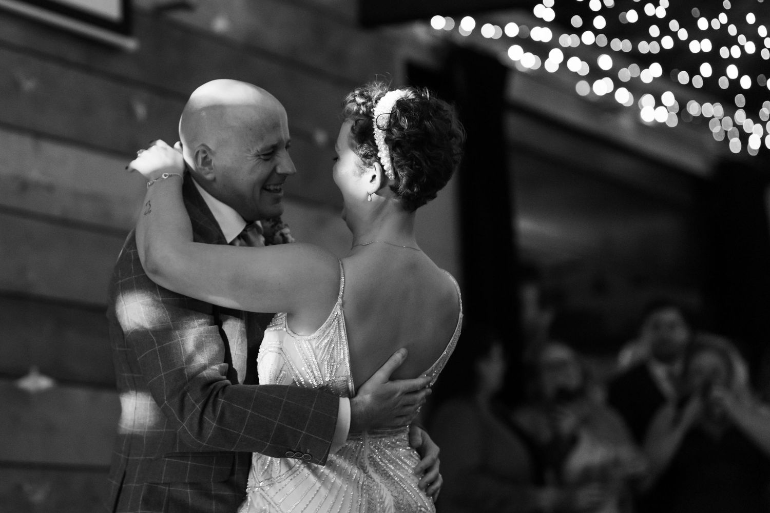 Couples dancing together under twinkling lights at an evening celebration.
