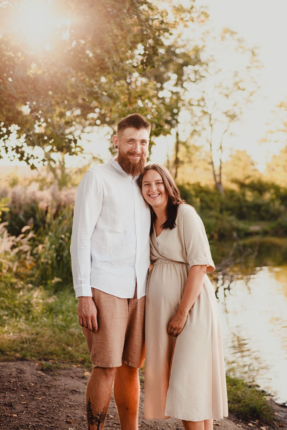 Happy family shares tender moment together by river during sunset photoshoot.