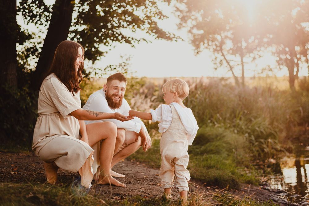 Sweet family interaction on riverbank during warm sunset lighting.