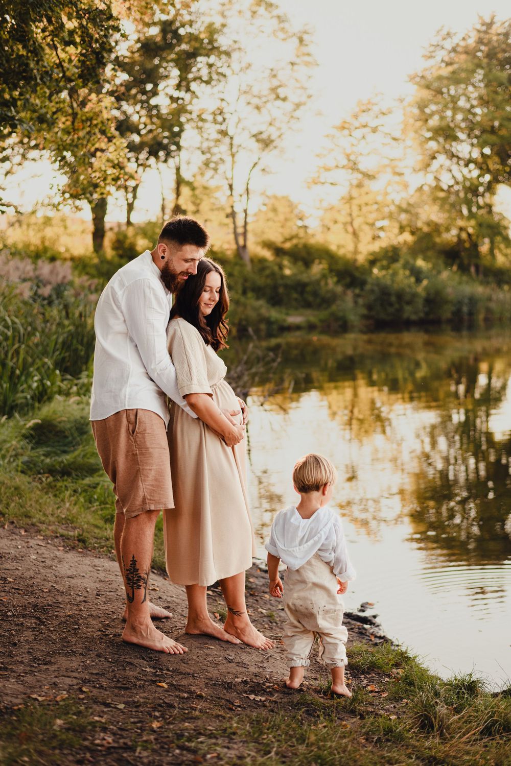 Family enjoying tender moments together by lake shore at golden hour.