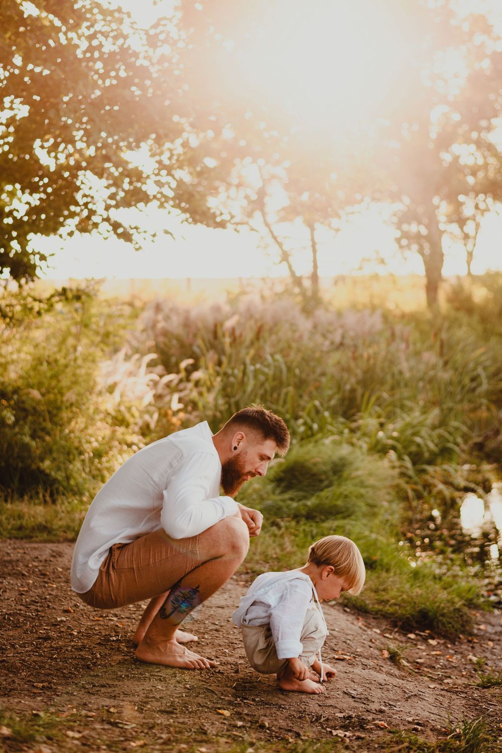 Playful interaction between parent and child on dirt path during sunset.