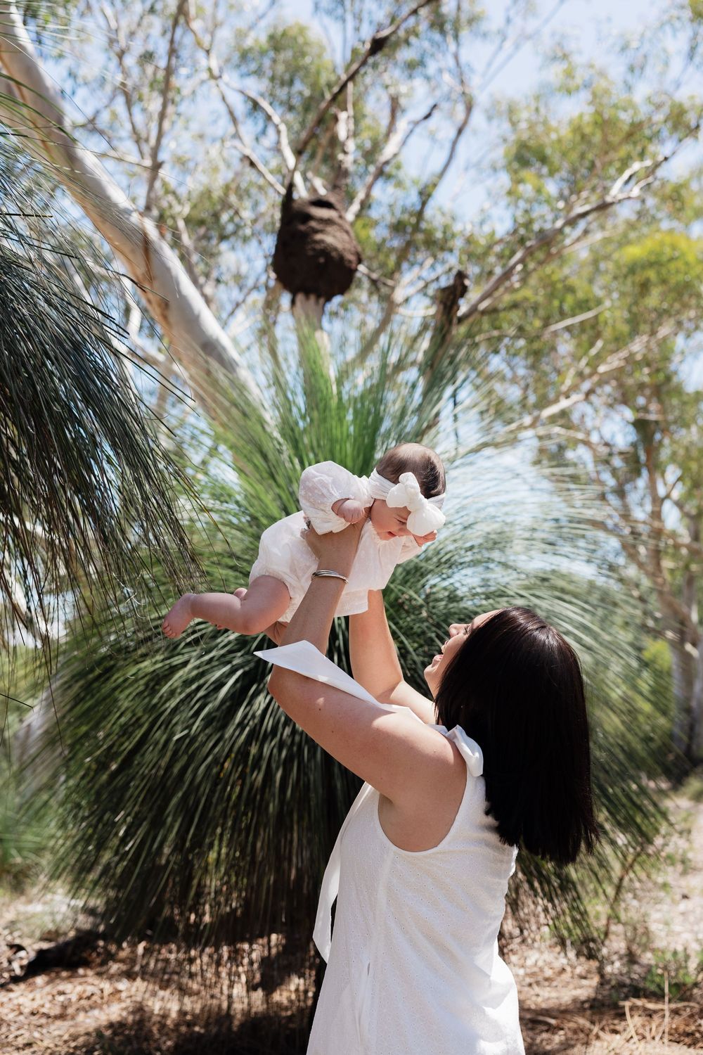 A person in white releases a dove into the air near native grass trees in an outdoor nature setting.