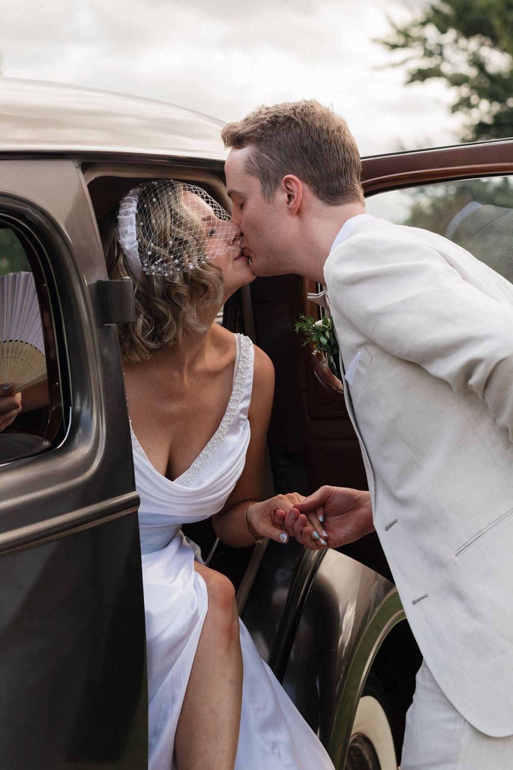 A romantic sequence of a couple sharing a kiss through a car window in a white and elegant setting.