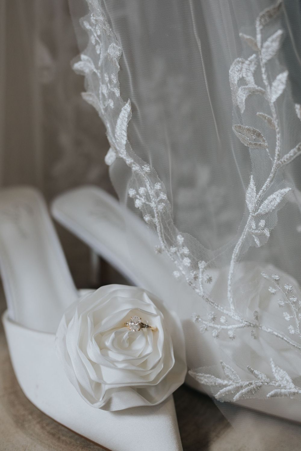Delicate white rose detail on sheer lace wedding veil with embroidered floral pattern.