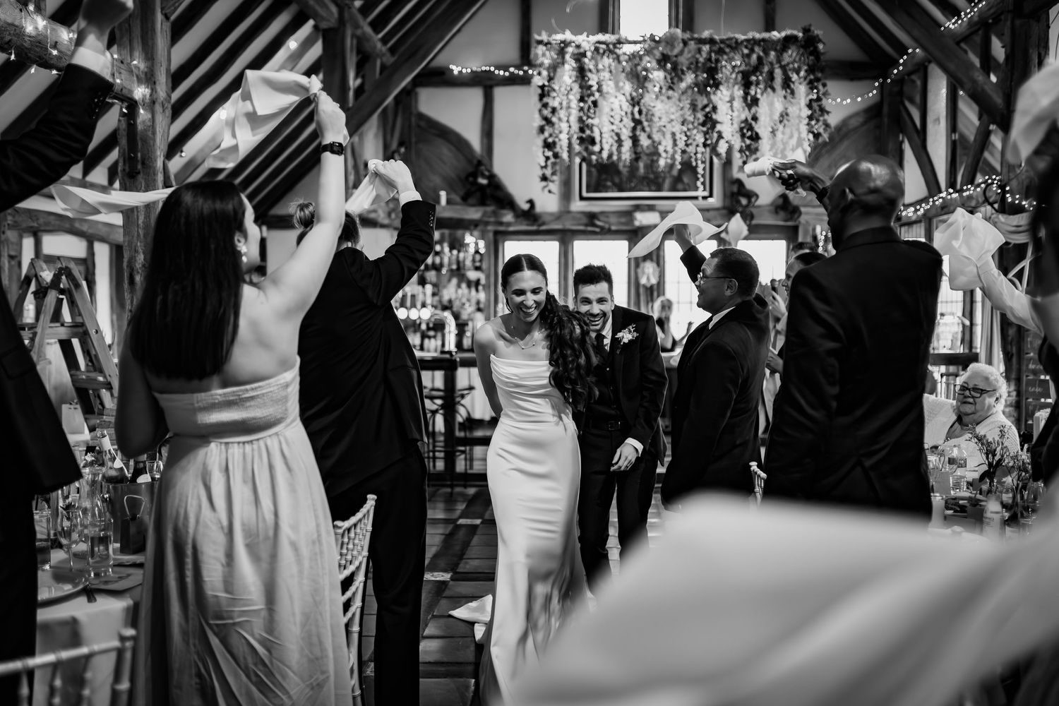 An elegant wedding portrait captured under a stone archway surrounded by lush greenery.