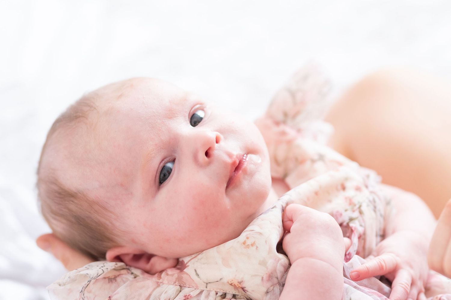 Serene natural light portrait of newborn baby in soft white tones.