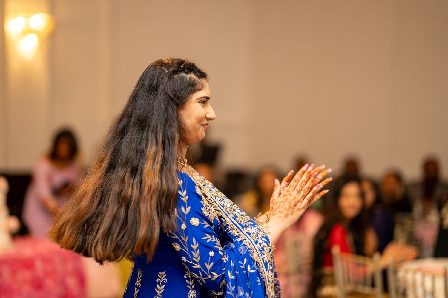 Woman in blue traditional Indian outfit dancing at cultural celebration.
