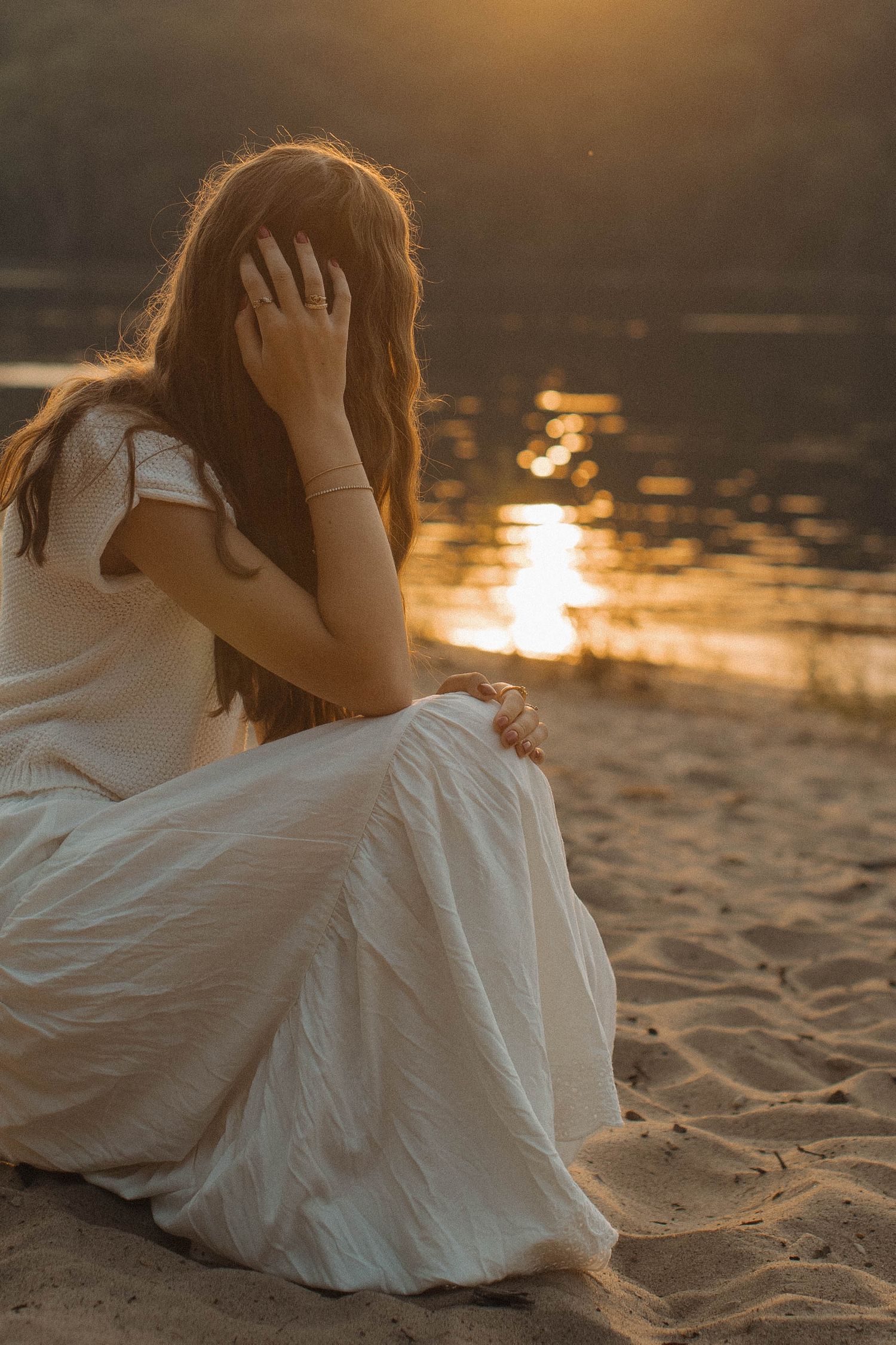 A white wedding dress flows gracefully on sandy beach at golden hour.