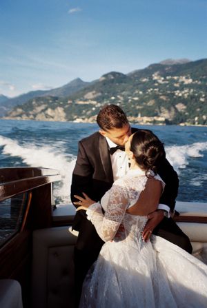 Bride and groom sharing a kiss on a boat with stunning Italian lake scenery.