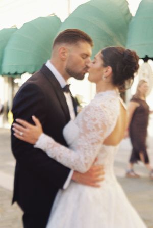 Bride and groom sharing a passionate kiss under green awnings in a beautifully candid wedding moment.