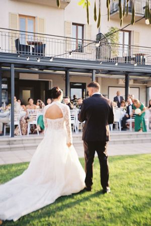 Bride and groom walking toward outdoor wedding reception guests at an Italian villa.
