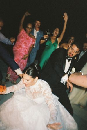 Bride and groom dancing energetically with guests at a lively wedding reception celebration.