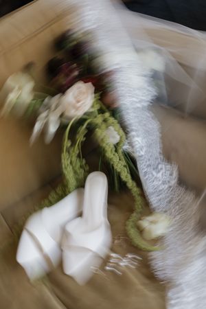 Blurred motion shot of a bridal bouquet with white and red roses, green garland, and white lace fabric.