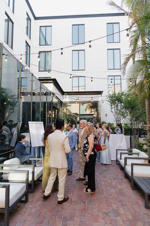 Guests mingle in a courtyard patio with string lights at an outdoor evening social event at a modern hotel.
