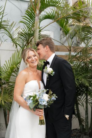 A happy couple shares an intimate wedding moment in front of tropical palm trees.