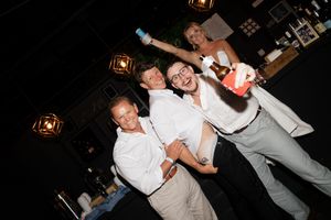 Party guests in white dress shirts enjoying themselves on the dance floor at an evening celebration.