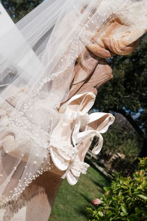 Delicate beaded wedding veil flowing in the breeze against a garden background.
