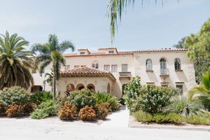 Mediterranean style villa with arched portico, white stucco exterior and lush tropical landscaping in Florida.