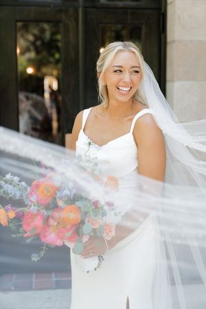A wedding dress and veil flow in the breeze while colorful flowers add a vibrant pop of color.
