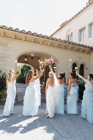Wedding party poses in front of Mediterranean-style architecture with arches and columns.