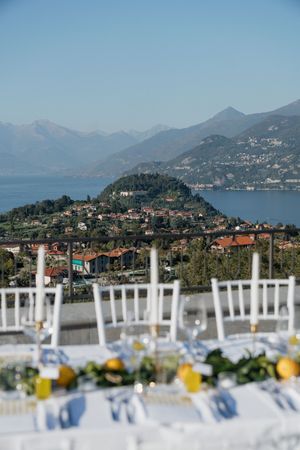 Stunning outdoor wedding reception table overlooking Lake Como with mountain views and lemon centerpieces.