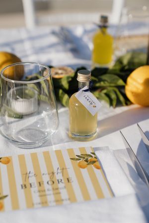Wedding table detail with limoncello favor bottle and lemon-themed stationery.