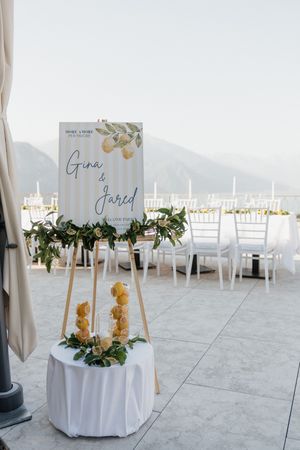 Elegant wedding welcome sign for Gina and Jared with lemon decor on an easel at an outdoor lakeside venue.