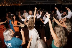 A large group of people dancing energetically with raised arms at a crowded nighttime party or event.