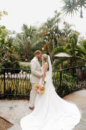 A romantic wedding photo series showing a couple twirling together on a palm tree-lined terrace in matching light outfits.