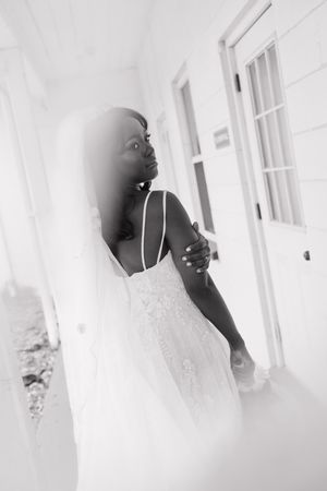 A dreamy black and white portrait of a person in a white dress gazing to the side against a white wall.