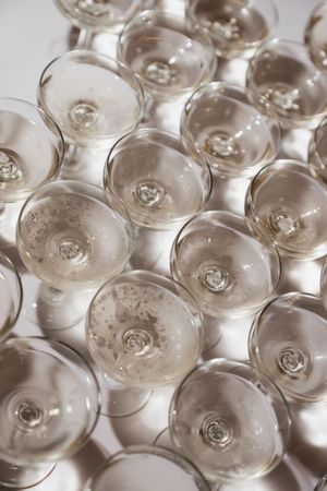 Overhead view of multiple champagne coupe glasses arranged on a white surface for a wedding reception.